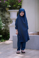 A side view of a little girl's loose-fit teal color Ramie Cotton Jilbab set for Hajj and Umrah, showing the lightweight draping of the head covering and matching trousers
