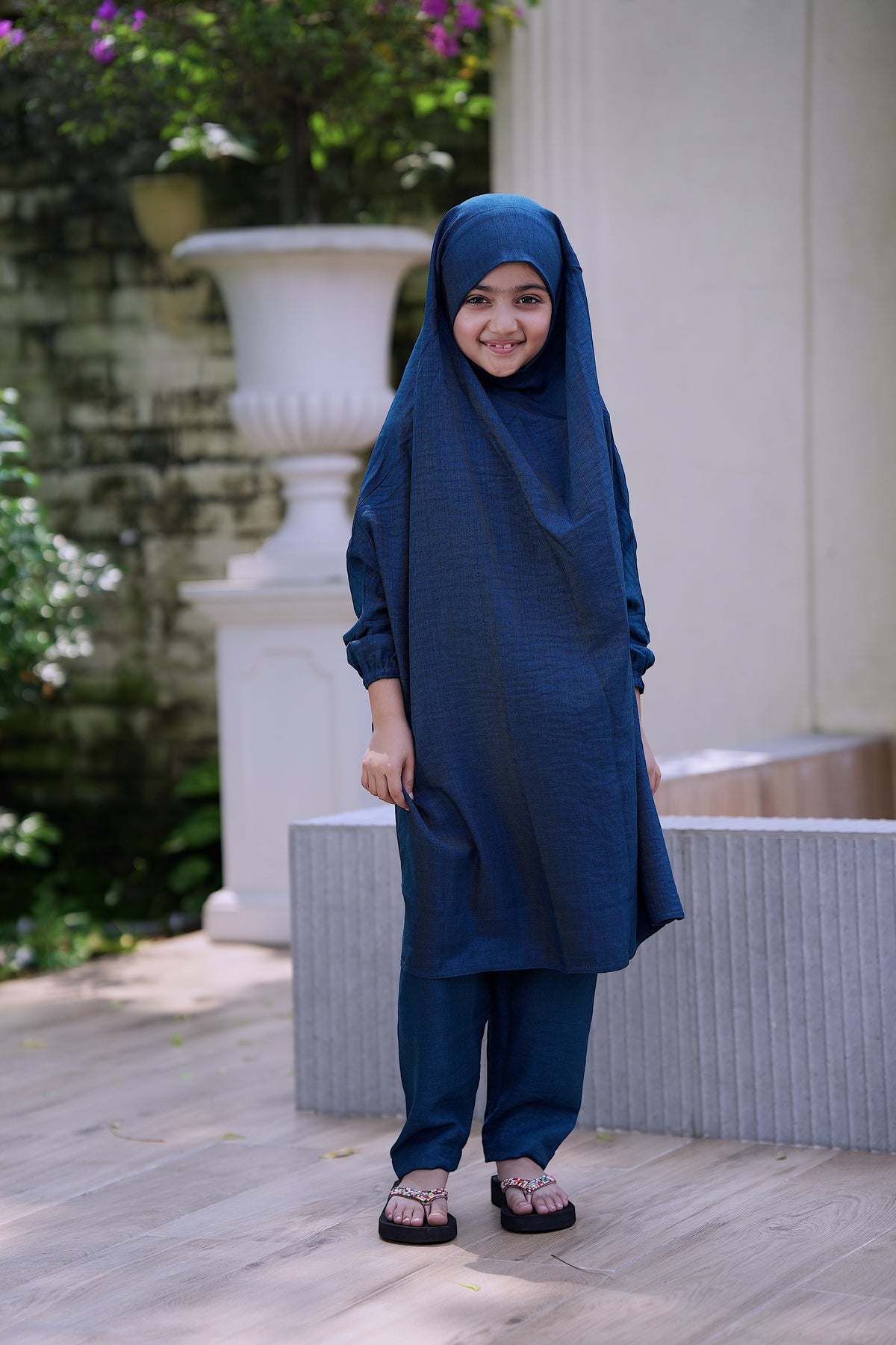 A side view of a little girl's loose-fit teal color Ramie Cotton Jilbab set for Hajj and Umrah, showing the lightweight draping of the head covering and matching trousers