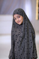 Closeup portrait of girl wearing grey polka dot baby khimar, elegant modest Islamic wear for children and Umrah

