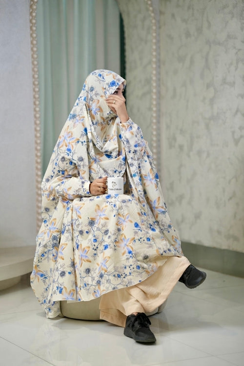 A woman wearing a beige and blue floral khimar and matching pants 
