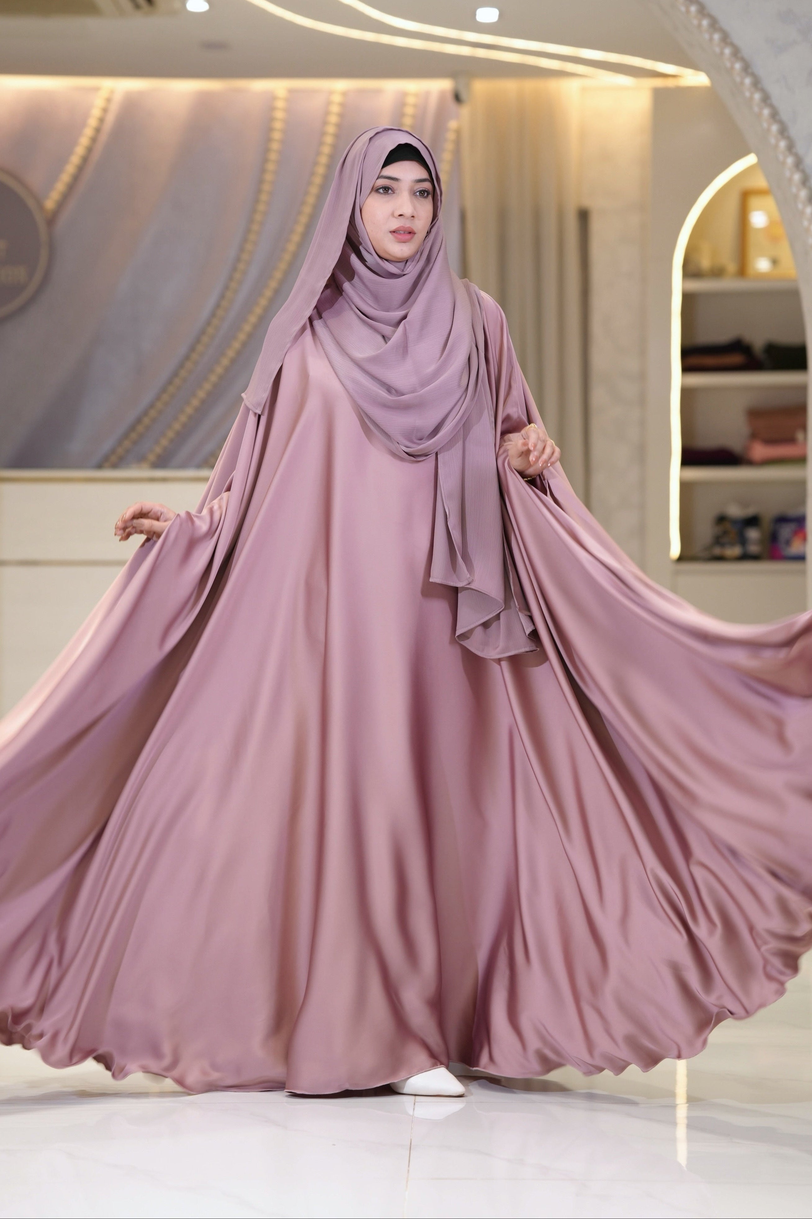 A luxurious rose-pink Orchid Silk abaya featuring a fluid drape, elegant soft sheen, and wide sleeves. A premium modest dress ideal for wedding guest attire, festive celebrations, and special occasions.