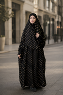 Woman wearing a black polka dot abaya on a city street.