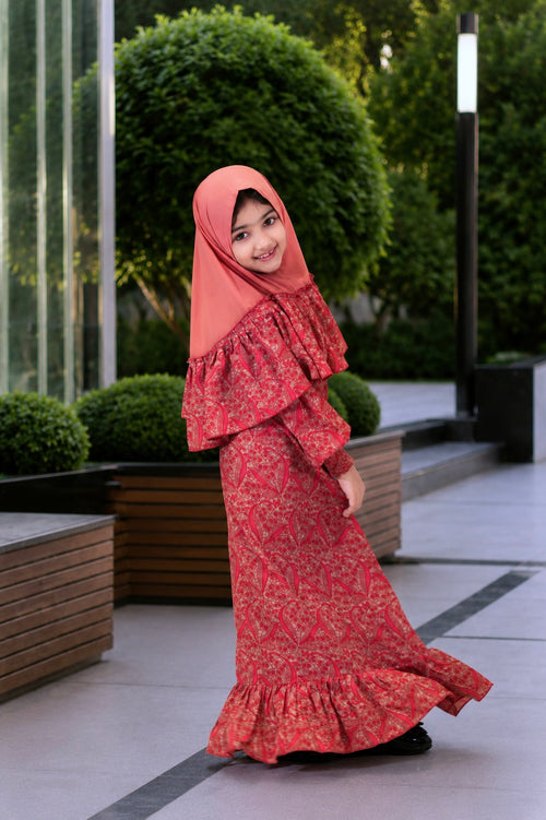 A young girl wearing the Little Lyra modest georgette dress with frill details and matching hijab.
