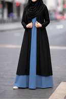 Woman wearing a black and blue abaya on a city street.