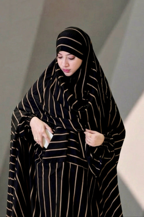 Front view of a woman wearing the black and gold striped Urban Stripe Khimar, demonstrating the functional side pocket.