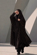 Full-length side profile of a woman modeling the Urban Stripe Khimar in black and gold georgette fabric.